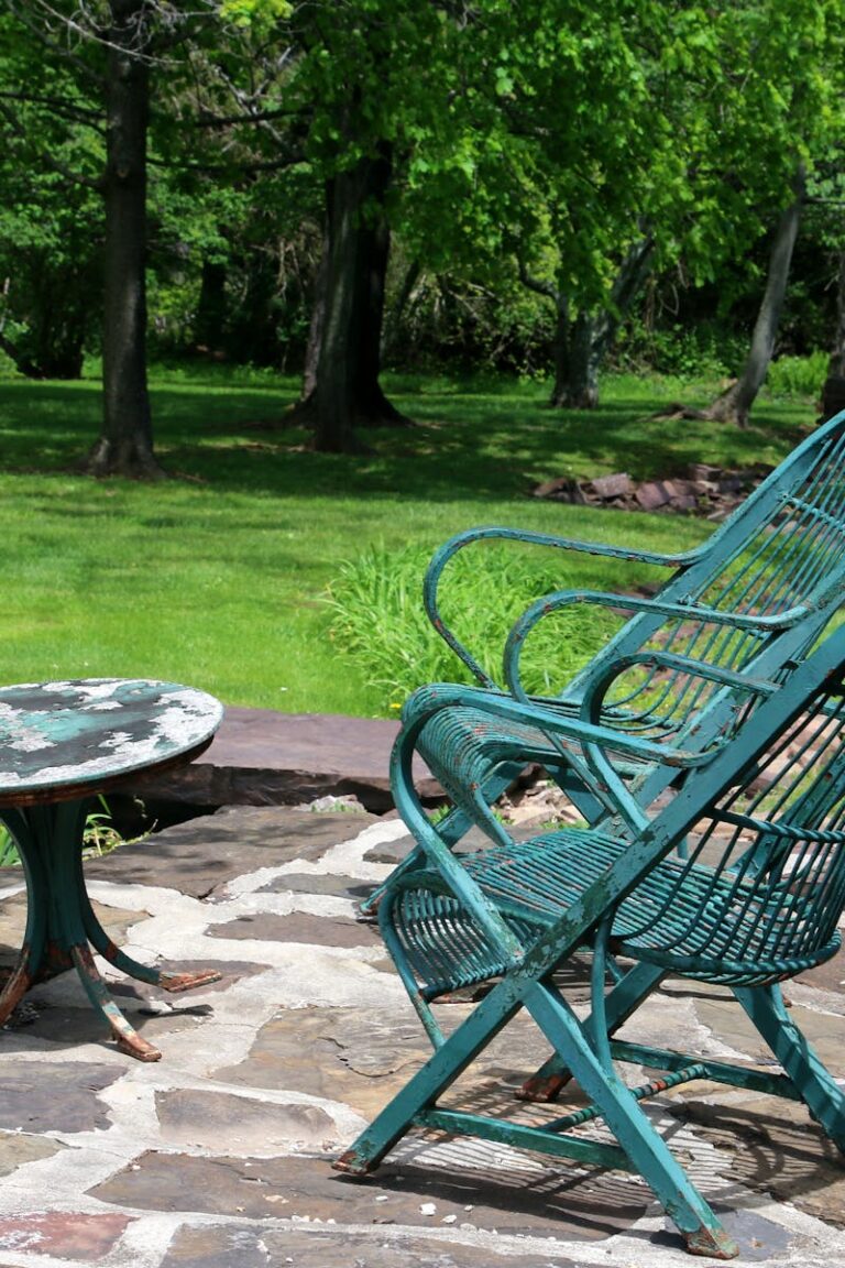 Peaceful outdoor seating area with metal chairs and table in a green garden.